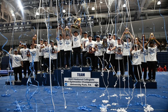Stanford gymnastics celebrating with a championship banner beneath falling confetti